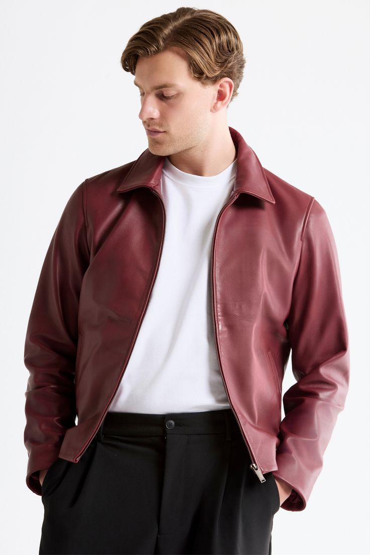 Man wearing a oxblood leather jacket over a white shirt on a white background