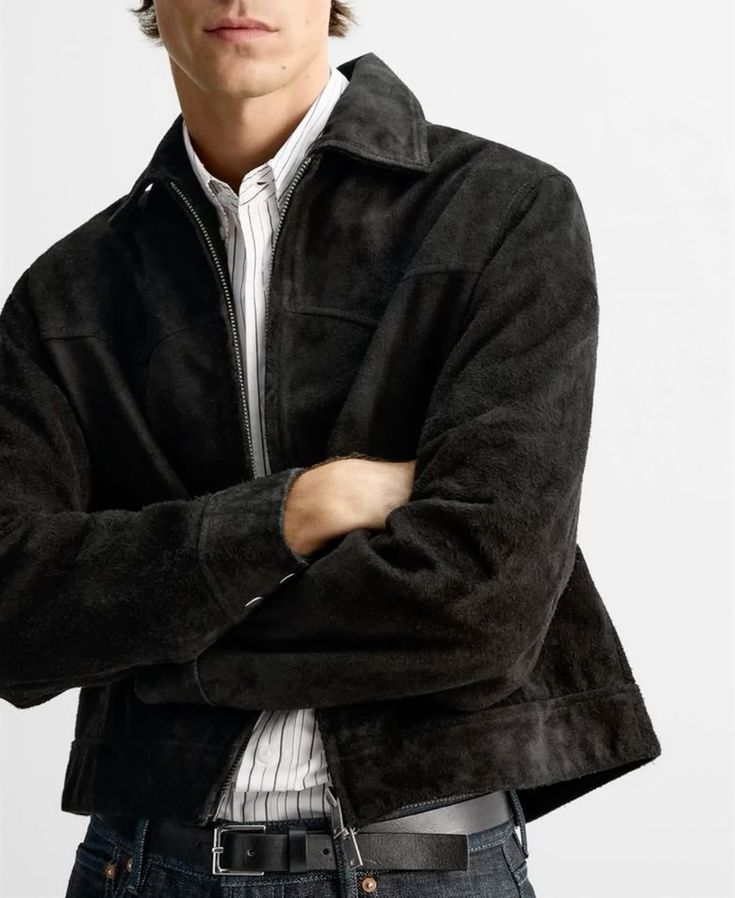 Man wearing a black suede jacket over a white shirt on a light gray background